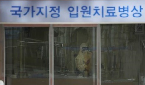 A staff member at Seoul National University Hospital in Bundang, south of Seoul, is in a full protective suit waiting to check people entering the entrance on Jan. 29, 2020. (Yonhap)