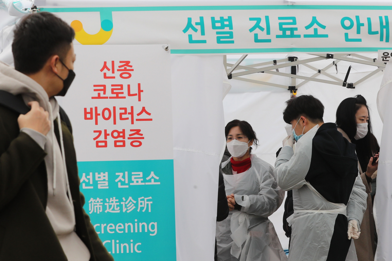 1일 오후 서울 중구 명동역 인근 거리에 신종 코로나바이러스 감염증의 유입과 확산을 방지하기 위해 설치된 중구보건소 선별진료소 앞으로 관광객이 지나가고 있다. [연합제공]