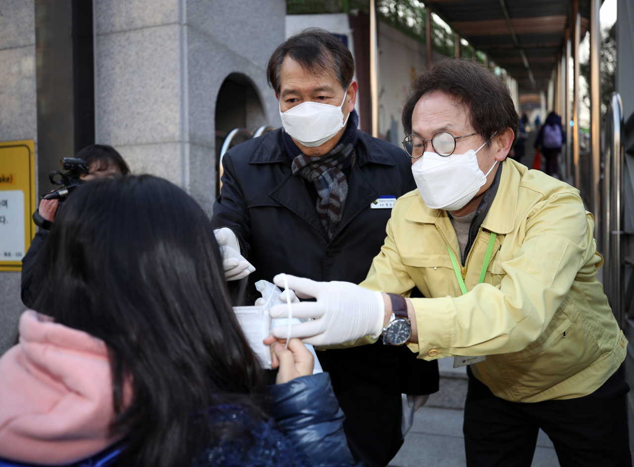 조희연 서울시 교육감이 3일 오전 서울 봉은초등학교에서 신종 코로나바이러스 감염증 예방 등을 위해 등교하는 학생에게 마스크를 건네고 있는 모습. [연합뉴스]