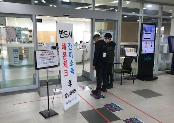 마포중앙도서관 자료열람실 입실 전 신종 코로나바이러스 예방을 위해 발열 체크 및 간이 소독을 하고있는 모습. [마포구 제공]
