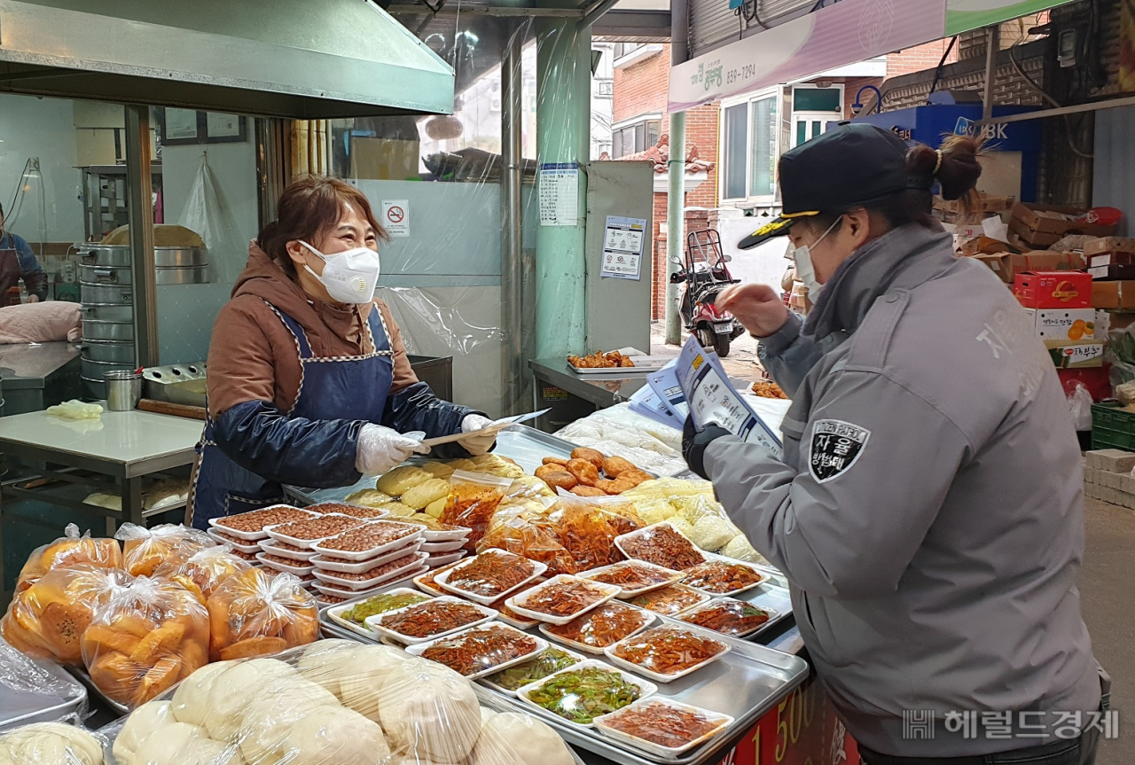 신사동 외국인자율방범대원이 지역 상인을 찾아 신종 코로나 예방행동수칙 안내문을 전달하고 있다. [관악구 제공]