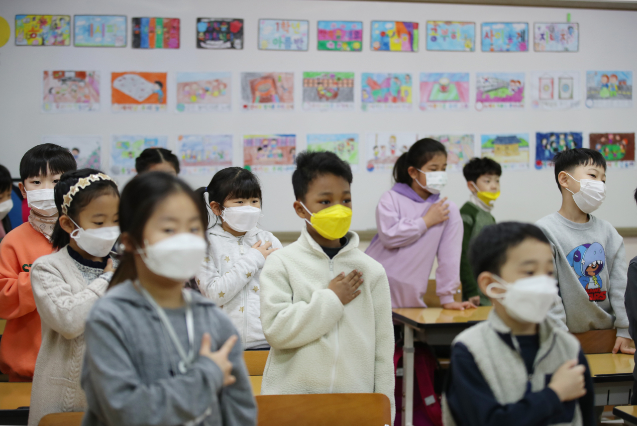지난 달 30일 오전 개학한 서울 용산초등학교에서 신종 코로나바이러스 감염증 예방을 위해 마스크를 쓴 어린이들이 국기에 대한 경례를 하고 있다. [연합]