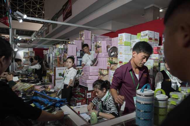 North Korean staff stand behind the counter of the kitchenware booth of a distributor from Thailand at the International Trade Fair in Pyongyang in 2017. (AFP-Yonhap)