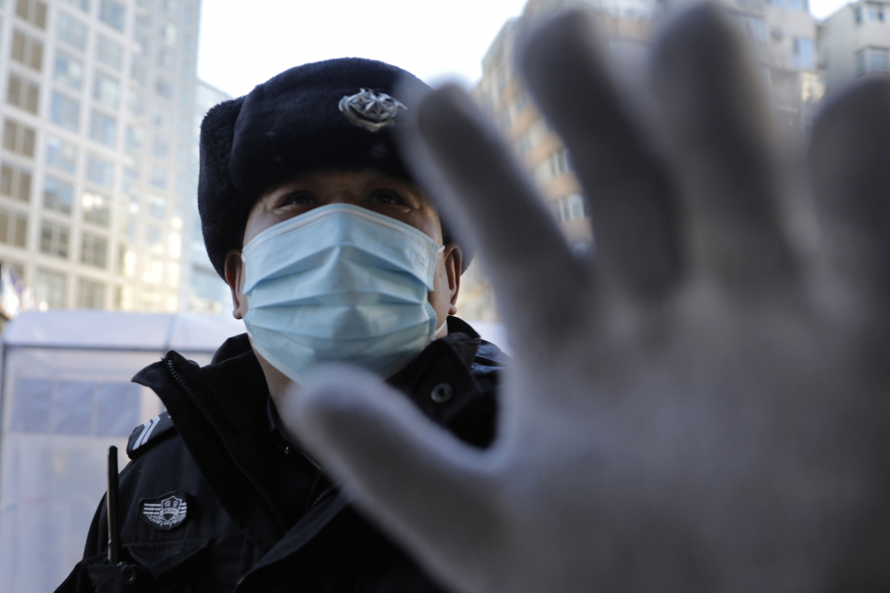 중국 내 신종 코로나바이러스 감염증(코로나19) 확진환자와 사망자가 각각 7만명과 1800명을 넘어선 가운데 베이징의 한 주택가에 들어가는 사람들을 소독하기 위해 설치된 비닐 천막 앞에서 경비원이 손으로 사진촬영을 제지하고 있다. [EPA]