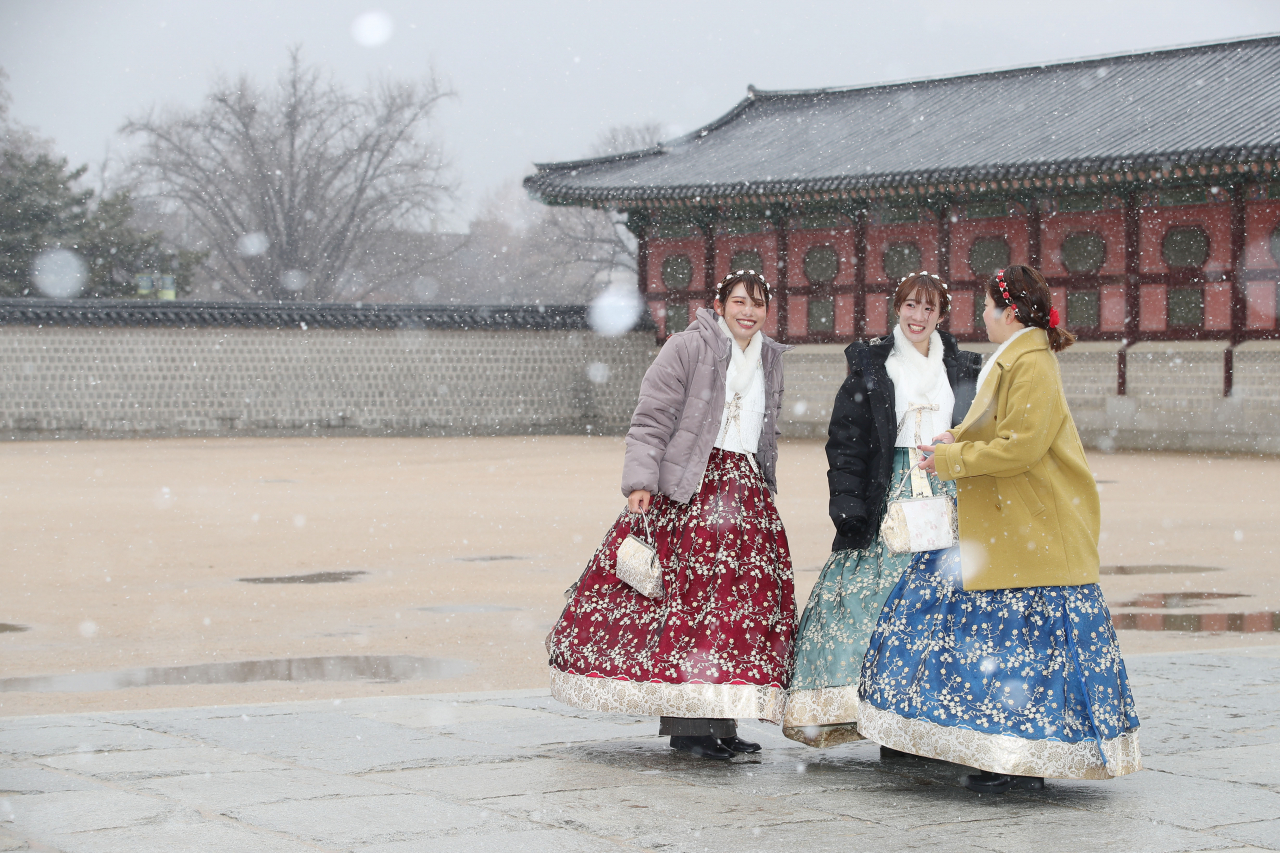 서울에 대설주의보가 내려진 16일 오전 한복을 입고 서울 종로구 경복궁을 찾은 외국인 관광객이 함박눈을 맞으며 이야기를 나누고 있다. [연합]