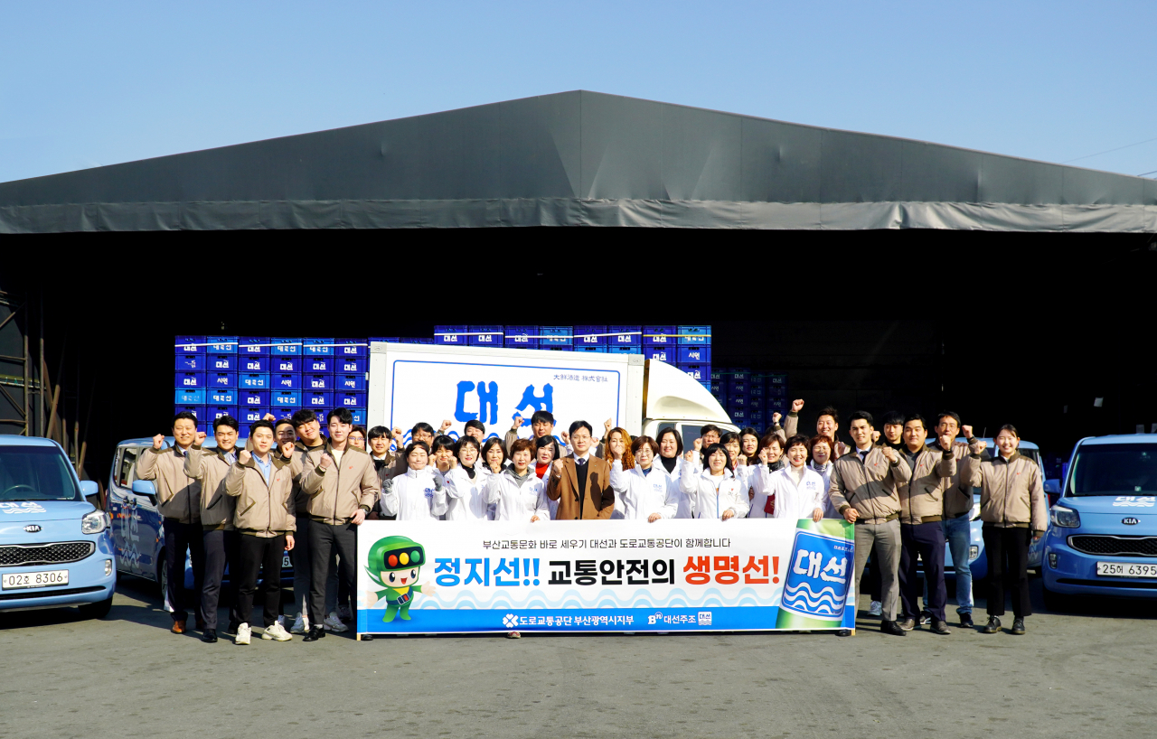 지난 14일 대선주조 사직동 본사에서 대선주조 임직원들과 도로교통공단 안전교육부 최진호 교수(가운데)가 교통사고 예방 공동홍보를 위한 기념촬영을 하고 있다.