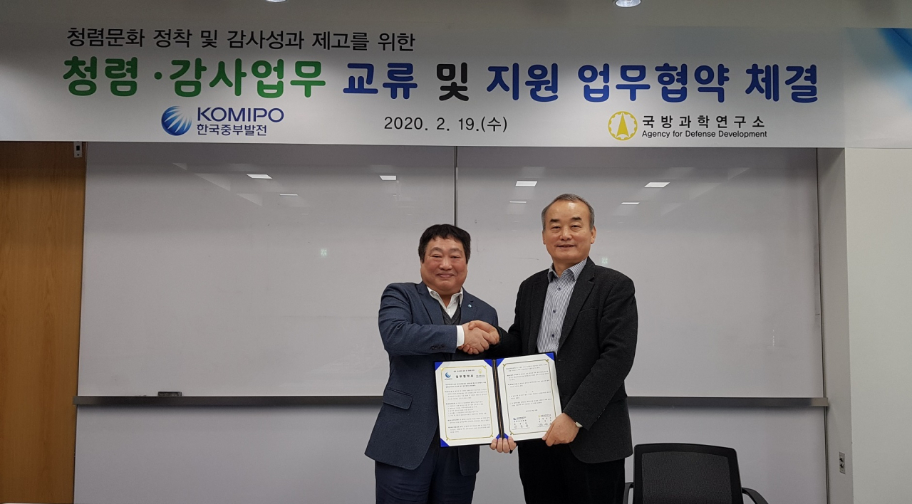 김관호(오른쪽) ADD 상임감사와 한동환 한국중부발전 상임감사위원이 업무협약서를 작성한 후 기념촬영을 하고 있다.[ADD 제공]
