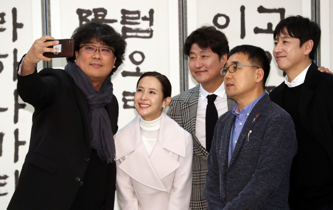 영화 ‘기생충’ 봉준호 감독과 배우 송강호, 조여정, 이선균 등이 지난 20일 청와대에서 문재인 대통령 초청 오찬에 앞서 기념촬영을 하고 있다. 앞줄 오른쪽은 봉 감독의 대학동기인 육성철 청와대 행정관. [연합]
