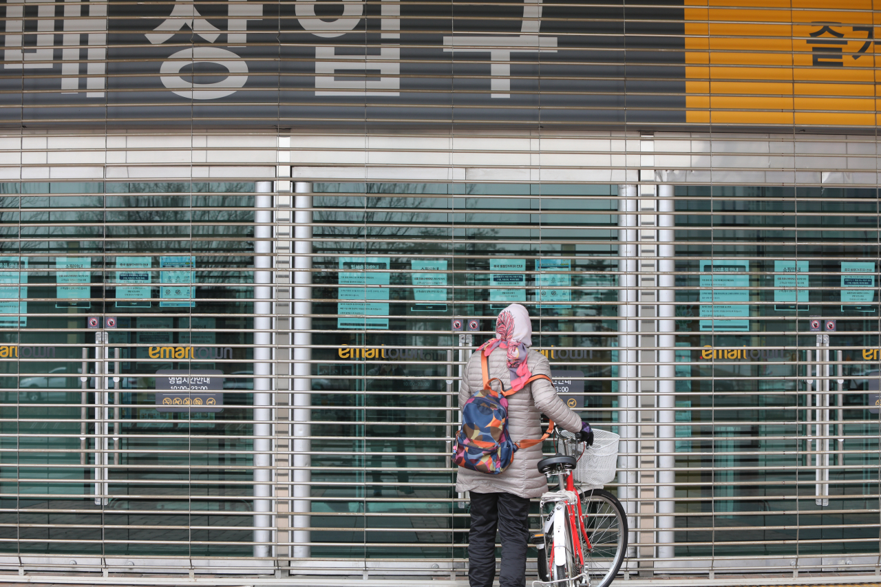 21일 오전 경기 고양 일산 이마트타운 킨텍스점 입구에서 한 주민이 임시휴점 안내문을 읽고 있다. [연합]