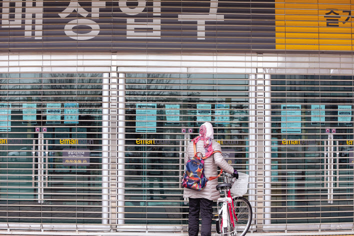 21일 오전 경기 고양 일산 이마트타운 킨텍스점 입구에서 한 주민이 임시휴점 안내문을 읽고 있다. [연합]