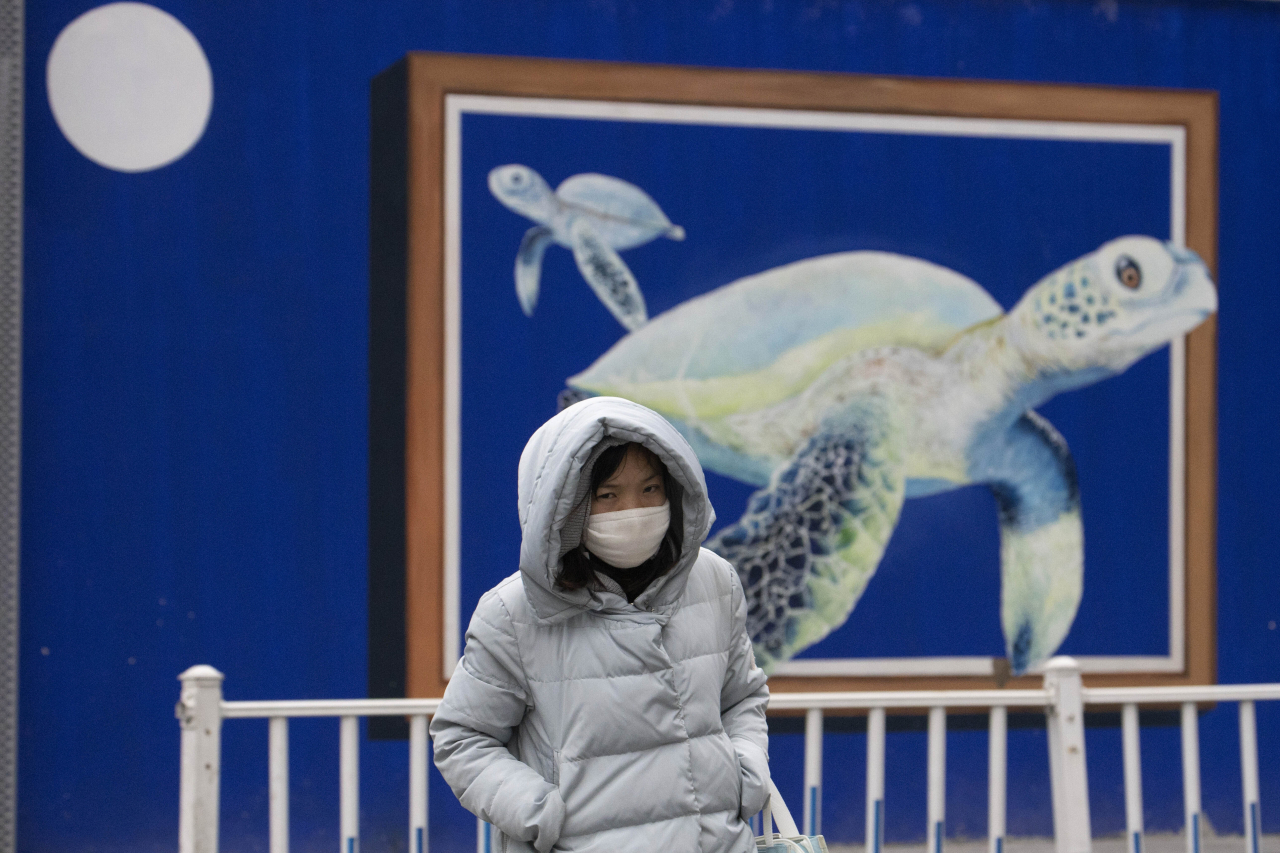 중국 베이징의 한 여성이 25일 마스크를 낀 채 걸어가고 있다. [AP]