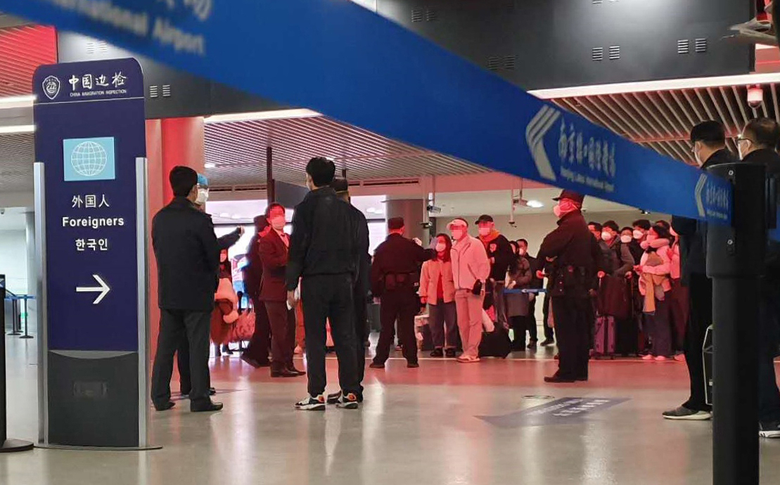 지난 25일 오후 중국 난징공항 입국장에서 한국 승객들이 줄을 서 방역 당국의 조사를 받고 있다. 입국장 외국인 안내판에 '한국인'이라는 글자가 적혀 있다. [연합]