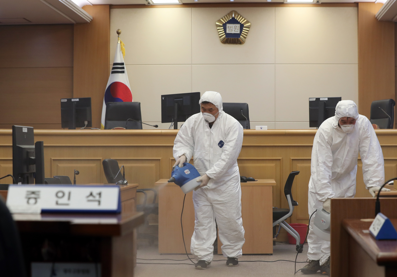 지난 25일 광주법원 법정에서 방역요원들이 코로나19로 휴정에 돌입한 내부를 방역하고 있다. [연합]