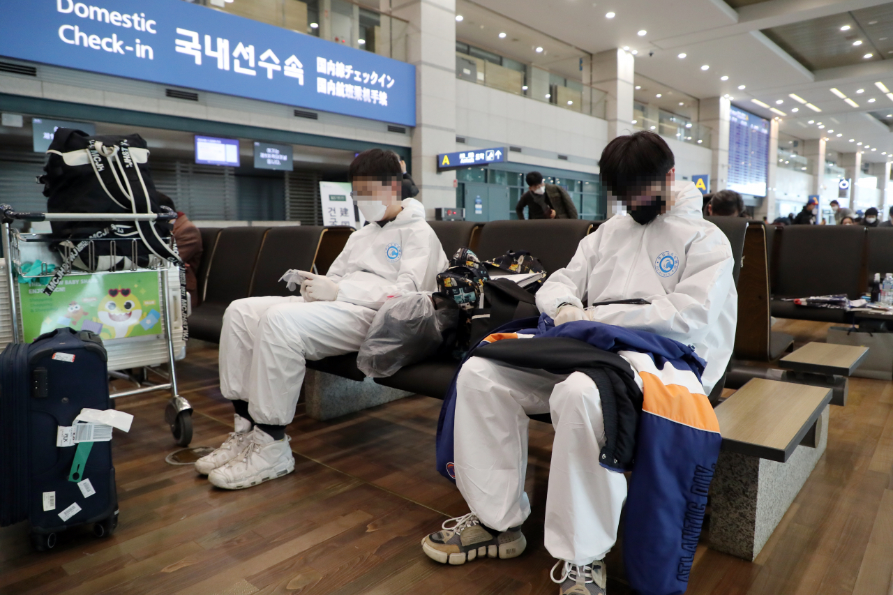 지난 25일 인천 중구 인천국제공항에서 보호복과 라텍스 장갑 등으로 중무장한 중국인 유학생들이 이동 전 대기하고 있다. [연합]