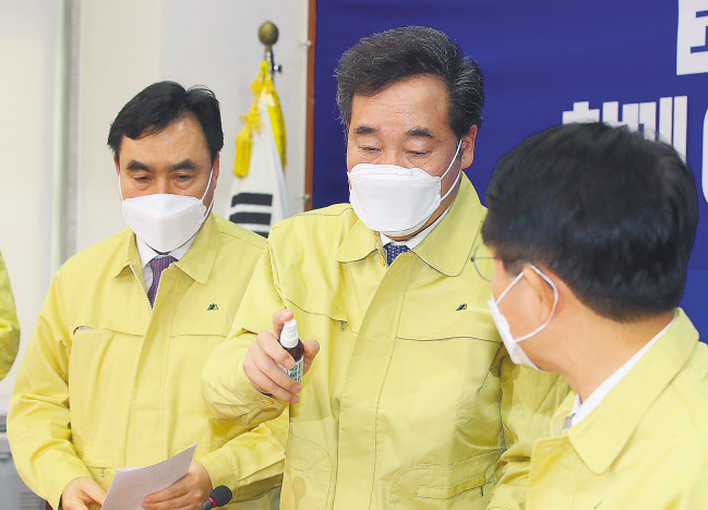 더불어민주당 코로나19 재난안전대책위원장을 맡은 이낙연 전 국무총리가 24일 국회에서 열린 간담회를 마친 뒤 참석자들에게 손소독제를 뿌려주고 있다. [연합]