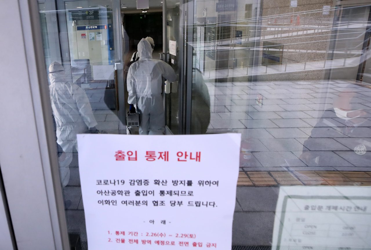 27일 서울 서대문구 이화여자대학교 신공학관 입구에서 방역업체 관계자들이 건물 내 소독을 위해 들어가고 있다. [연합]
