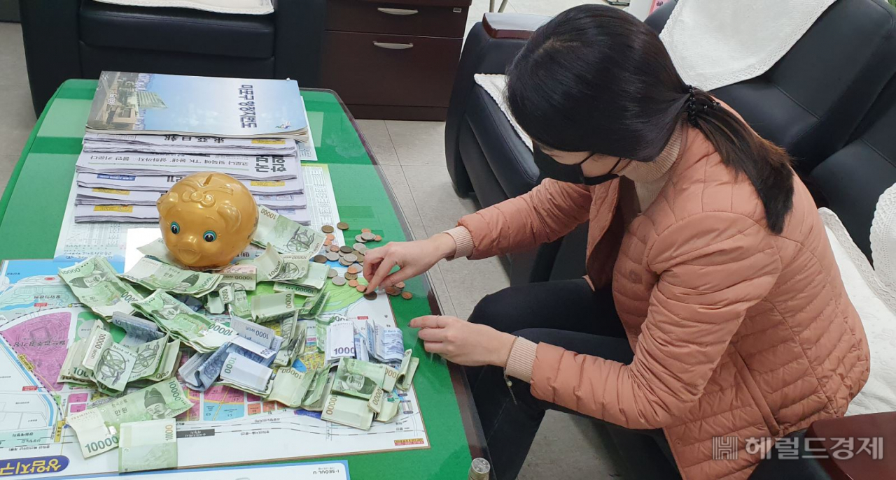 마포구 상암동 주민센터 직원이 익명의 중년남성이 홀연히 건넨 돼지저금통과 현금을 세고 있다. [마포구 제공]