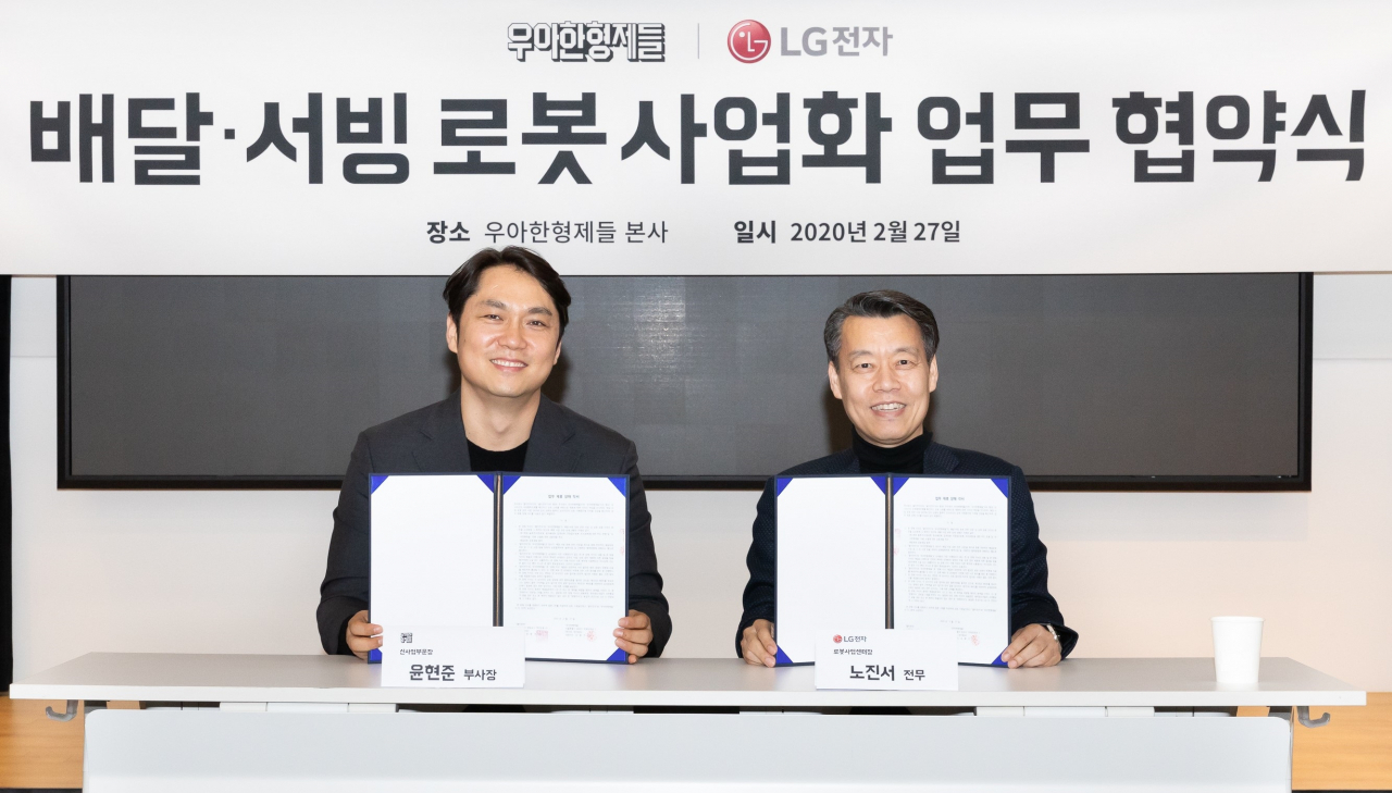 LG전자와 우아한형제들이 국내 로봇시장의 저변을 확대하기 위해 27일 서울 송파구 우아한형제들 본사에서 배달·서빙로봇 관련 사업협력을 위해 업무협약을 맺었다. LG전자 로봇사업센터장 노진서 전무(오른쪽)와 우아한형제들 신사업부문장 윤현준 부사장(왼쪽)이 기념촬영을 하고 있다. [LG전자 제공]