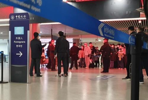 지난 25일 오후 중국 난징공항 입국장에서 한국 승객들이 줄을 서 방역 당국의 조사를 받고 있다. [연합뉴스]