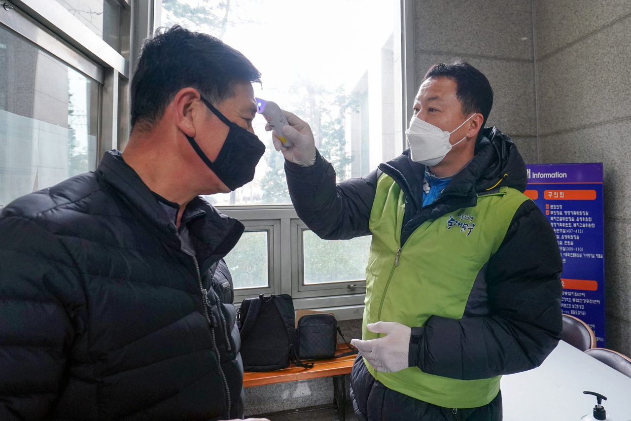 동대문구시설관리공단 소속 직원이 동대문구청 출입구에서 방문객의 체온을 측정하고 있다. [동대문구 제공]