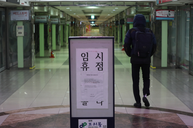 신종 코로나바이러스 감염증(코로나19)이 전국으로 확산되면서 실물경제에 큰 충격을 주고 있다. 사진은 코로나19의 직격탄을 맞은 대구에서 한 시민이 임시 휴점 안내문을 세워놓고 점포들이 모두 문닫은 중구 중앙로 지하상가를 홀로 걷고 있다. [연합]