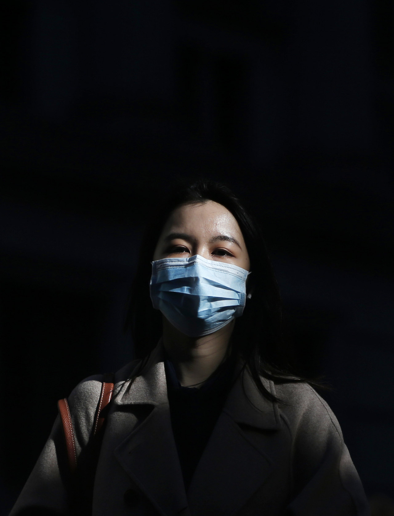 마스크를 착용한 여성이 미 월스트리트 뉴욕증권거래소 부근을 지나고 있다. [UPI]