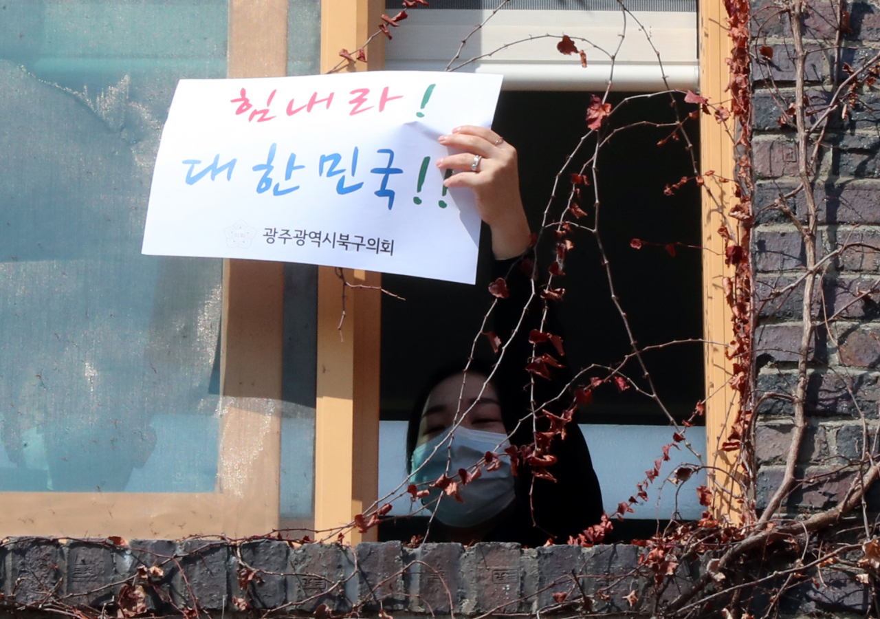 5일 오전 광주 북구청에서 구청과 북구의회 직원들이 코로나19 응원 문구가 적힌 종이를 들고 극복을 응원하는 퍼포먼스를 펼치고 있다. [연합]