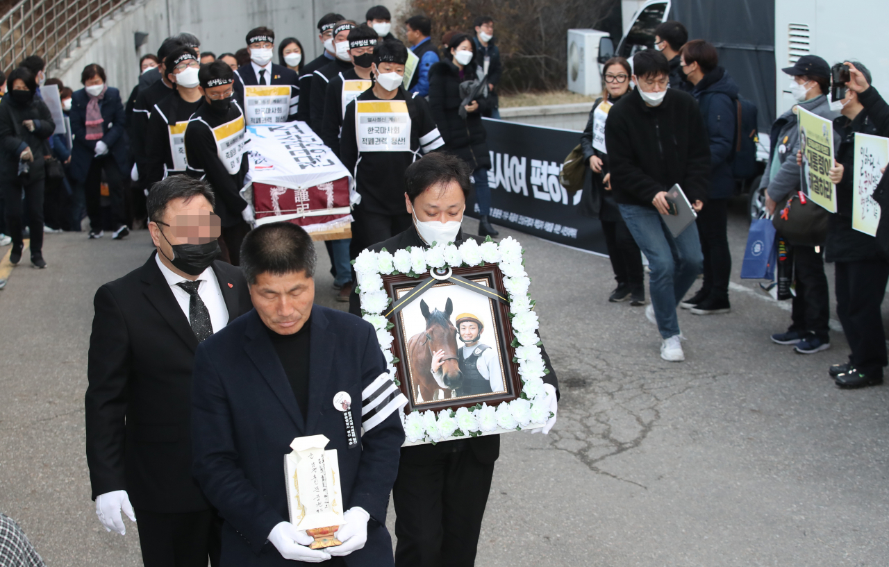 한국마사회의 부조리를 고발하며 극단적 선택을 한 고(故) 문중원 기수의 발인식이 9일 오전 서울 종로구 서울대병원 장례식장에서 열렸다. 고 문중원 기수 죽음의 진상규명과 책임자 처벌을 위한 시민대책위원회 인사들을 비롯한 ‘한국마사회 적폐권력 청산 문중원 열사 노동사회장 장례위원회 관계자들이 고인의 영정과 시신을 운구하고 있다. [연합]