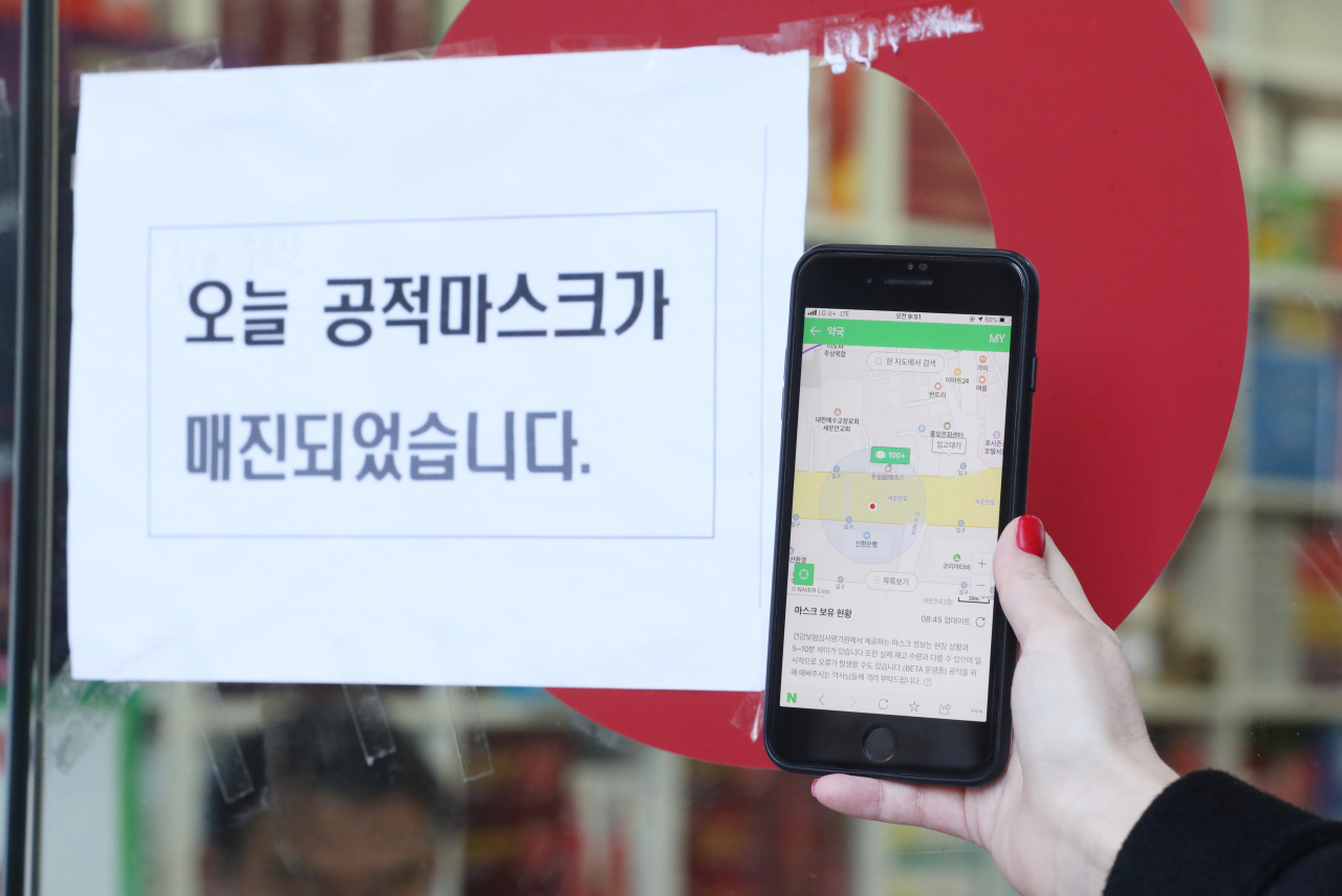 마스크 현황 애플리케이션(앱) 서비스가 시작된 11일 오전 서울 광화문광장 인근 한 약국 앞에서 시민이 앱을 통해 마스크 충분 상태를 확인한 뒤 방문했으나 마스크 품절 안내문이 붙어 있다. 이 약국에 따르면 공적 마스크 중복구매 확인 사이트 접속이 제대로 되지 않는 상황이라고 설명했다. [연합]