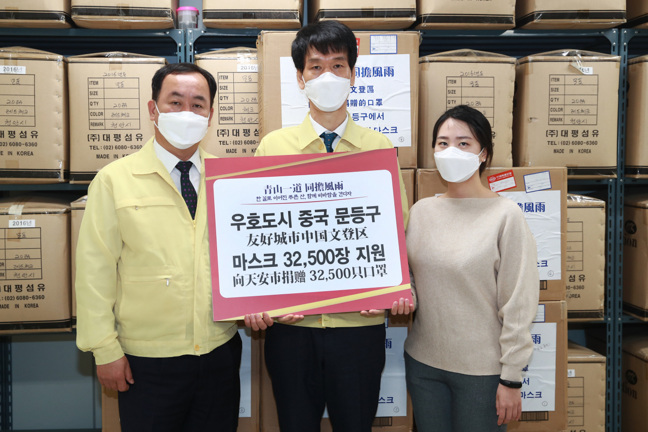 중국 웨이하이시 원덩구가 우호 도시인 충남 천안시에 보내온 마스크(3만2천500장)를 천안시 관계자가 12일 들어보이고 있다. 마스크 상자에는 '청산일도 동담풍우'가 적혀 있다. '한 길로 이어진 푸른 산, 함께 비바람을 견디자'라는 뜻이다. 2020. 3. 12 [천안시 제공. 재판매 및 DB 금지] 연합뉴스