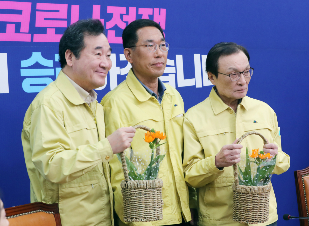 13일 서울 여의도 국회에서 열린 더불어민주당 코로나19 국난극복위원회·선거대책위원회 연석회의에서 이낙연 국난극복위원장(왼쪽), 이해찬 대표(오른쪽)가 김주영 공동선대위원장이 전달한 화분을 들고 화훼농가돕기 캠페인을 하고 있다. 연합뉴스