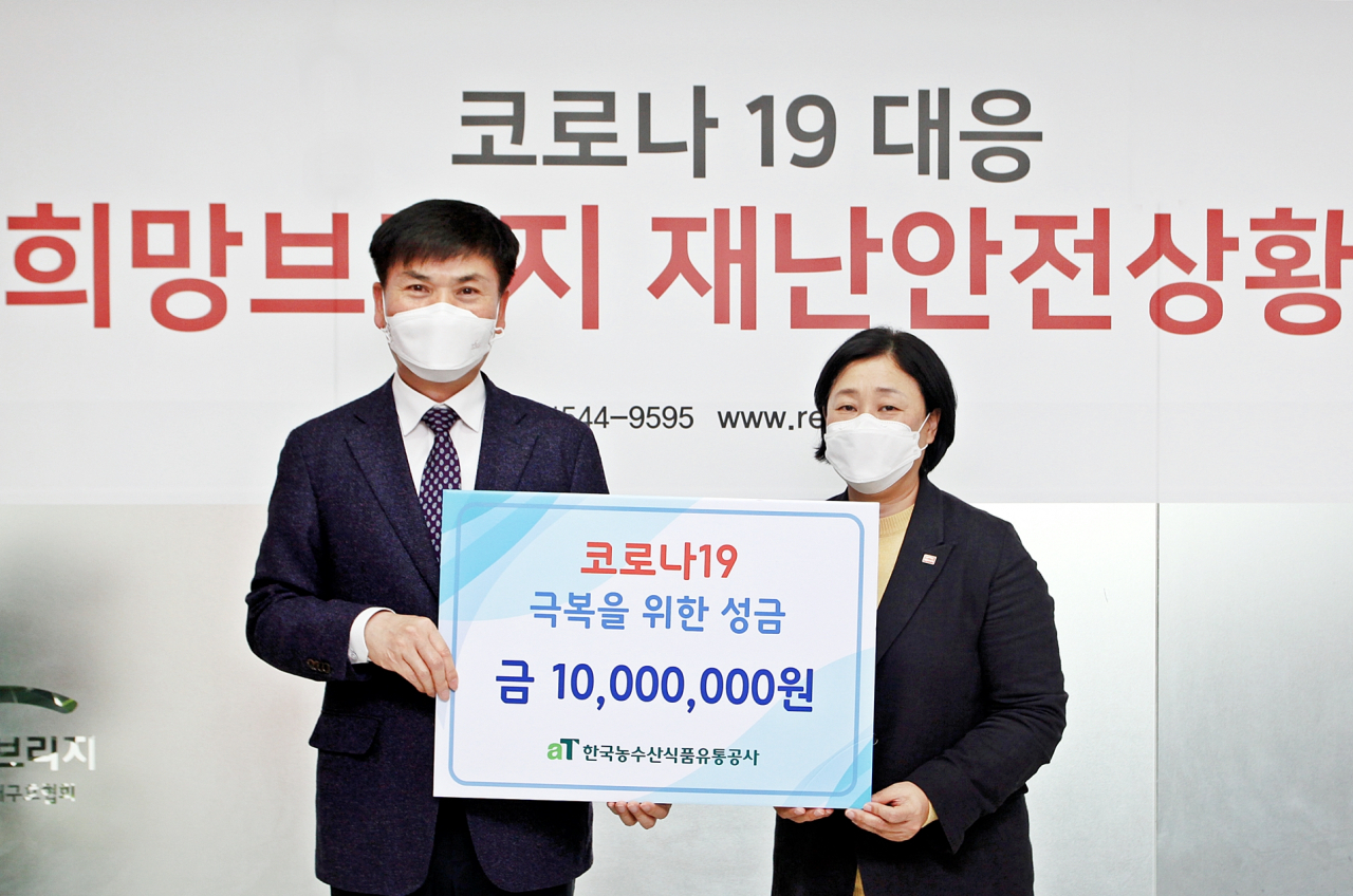 백진석 aT 부사장(왼쪽)이 김정희 전국재해구호협회 사무총장에게 코로나19 극복을 위한 성금증서를 전달하고 있다. [aT제공]