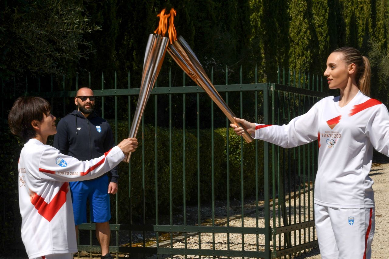 Torchbearer Greece's Anna Korakaki (right), Rio 2016 gold medallist in the 25m pistol shooting, gives the Olympic flame to Japan's Mizuki Noguchi, Athens 2004 women's marathon gold medalist, during the Olympic flame lighting ceremony on March 12, 2020 in ancient Olympia, ahead of the Tokyo 2020 Olympic Games. (AFP-Yonhap)