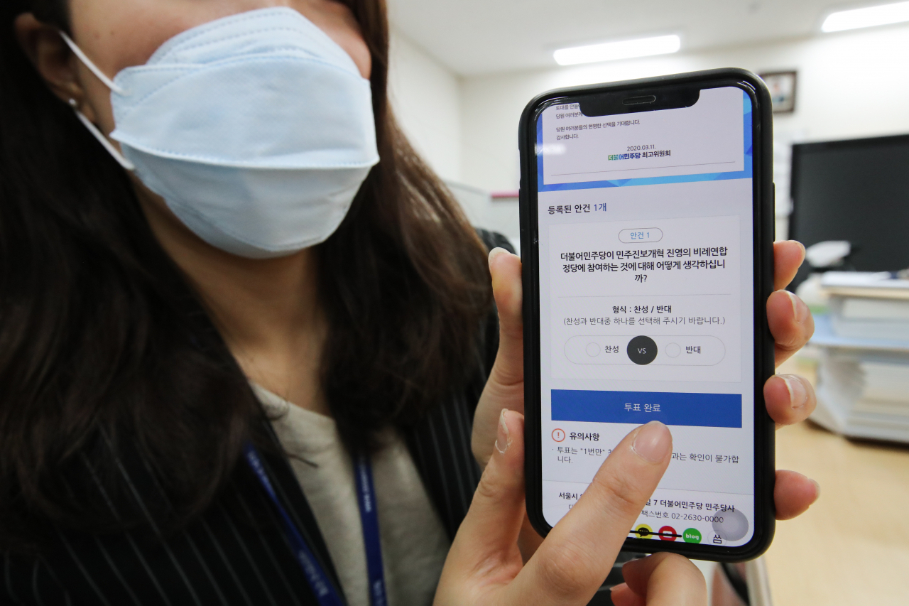 더불어민주당의 비례연합 참여 여부에 대한 온라인 투표가 실시된 지난 12일 국회에서 한 민주당 권리당원이 스마트폰으로 온라인 투표를 하고 있다. [연합]