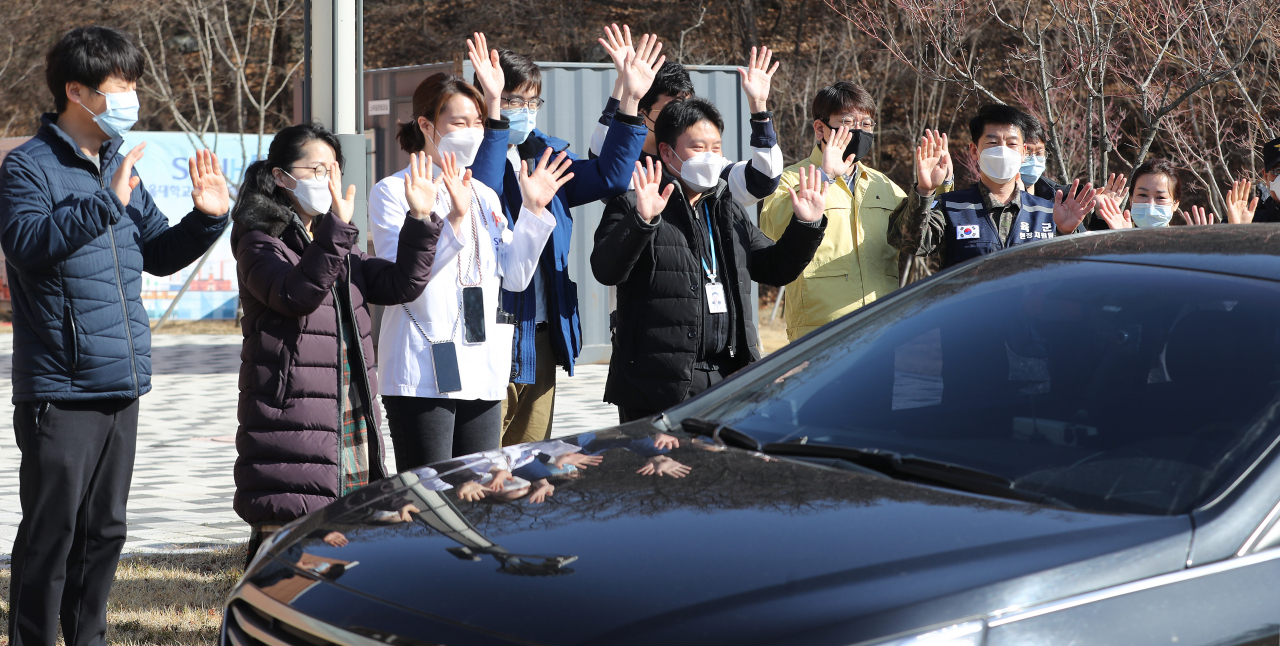 12일 경북 문경시 문경읍 서울대학교병원 인재원에 마련된 대구·경북 제3생활치료센터에서 이 센터에 입소한 신종 코로나바이러스 감염증(코로나19) 경증 확진자 가운데 첫번재 격리해제자가 차를 타고 치료센터를 떠나자 센터의 의료진과 관계자들이 손을 흔들며 작별 인사를 하고 있다. 연합뉴스