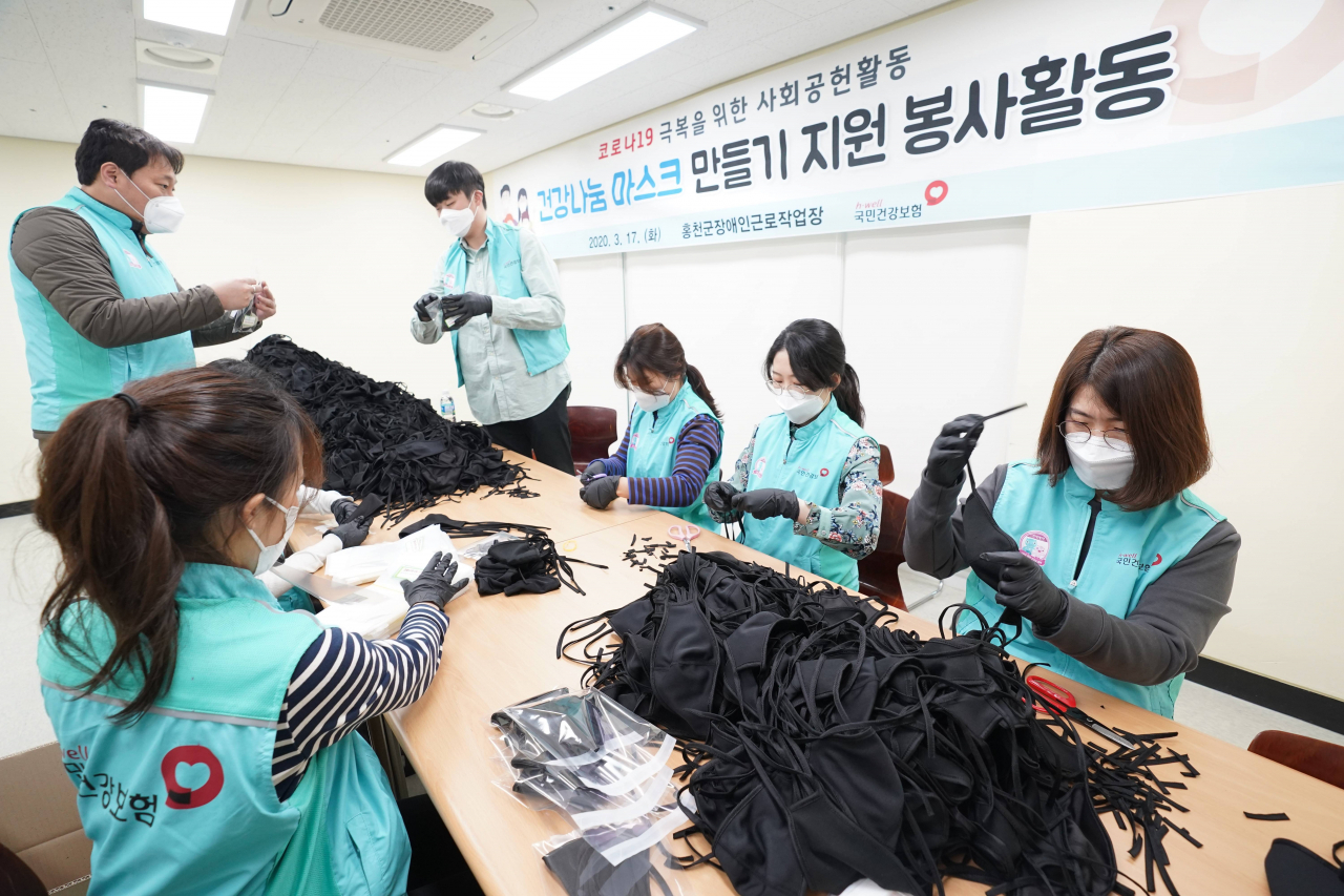 건보공단 임직원 20여명이 지난 17일 강원도 홍천군 장애인 근로작업장을 찾아가 직접 면 마스크를 만들고 있다. [건강보험공단 제공]