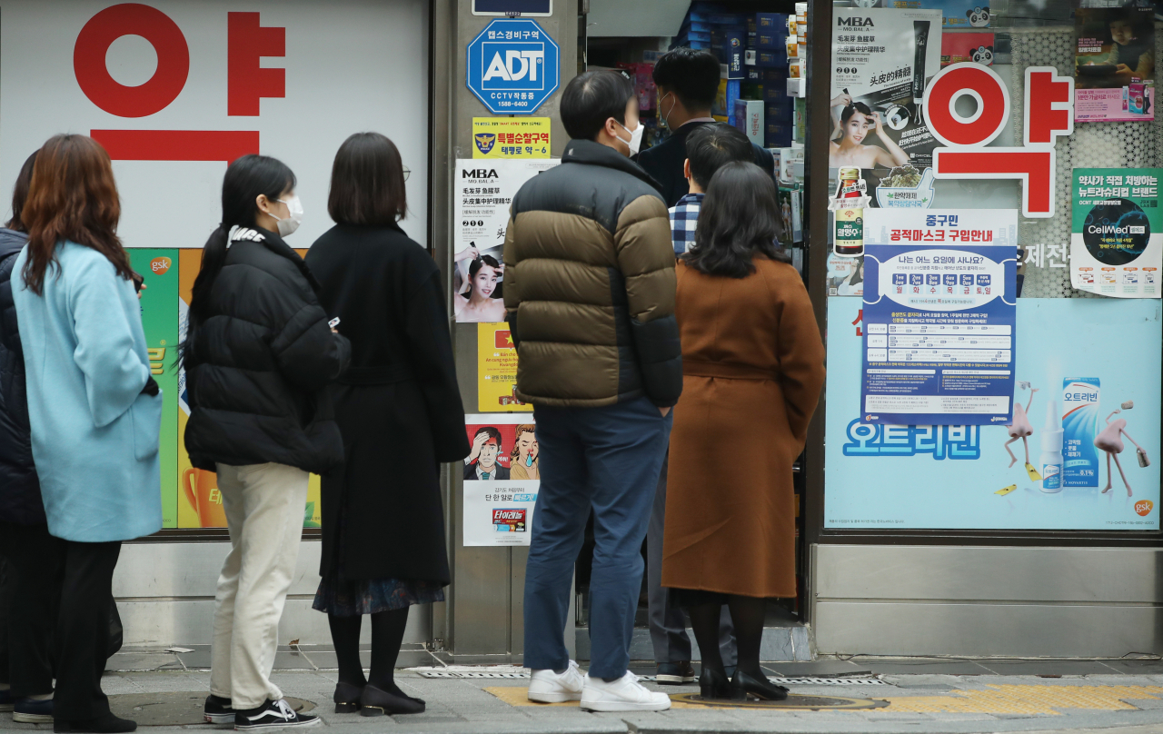 지난 17일 오후 서울 시내의 한 약국에서 시민들이 공적 마스크를 구매하기 위해 줄을 서고 있다. [연합]