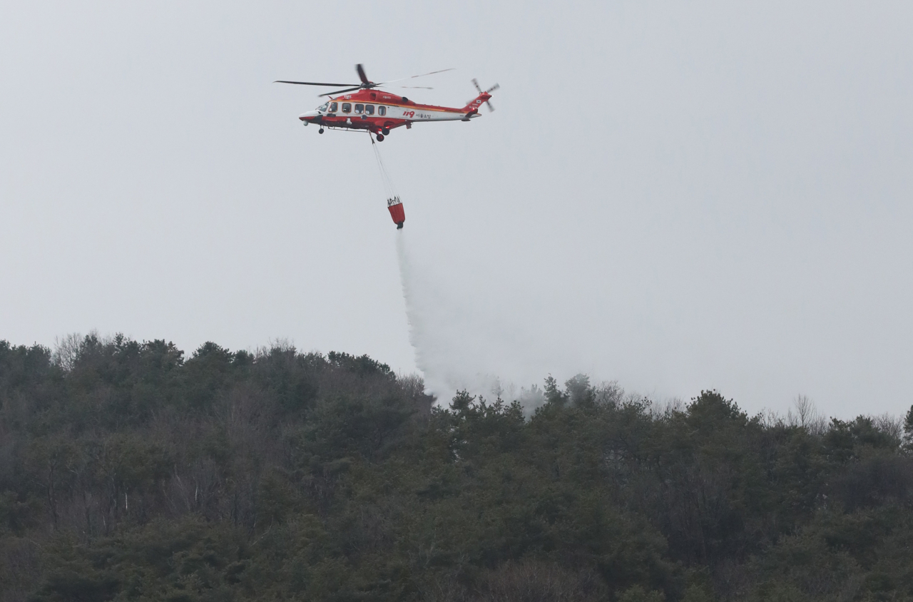 19일 오전 산불이 발생한 서울 노원구 수락산 귀임봉 인근 상공에서 소방 헬기가 물을 뿌리고 있다. [연힙]