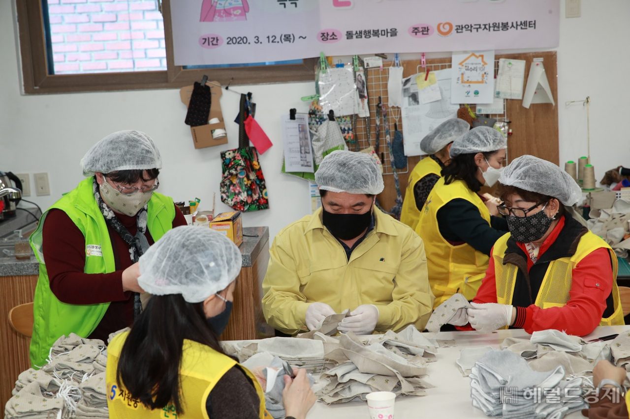 박준희 관악구청장(가운데 남성)이 자원봉사자들과 함께 면마스크를 만들고 있다. [관악구 제공]
