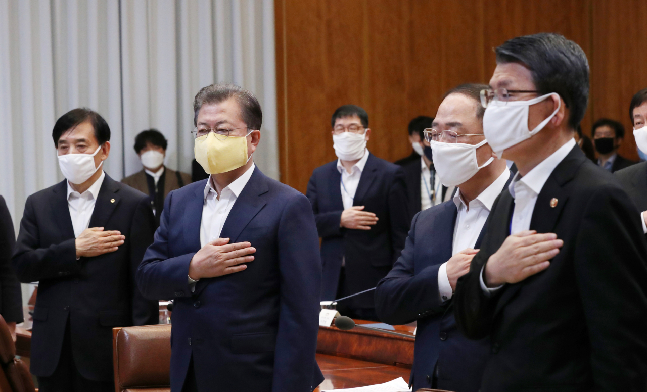 문재인 대통령이 19일 청와대에서 열린 코로나19 대응 논의를 위한 비상경제회의에서 국기에 경례하고 있다. 왼쪽부터 이주열 한국은행 총재, 문 대통령, 홍남기 경제부총리 겸 기획재정부 장관, 은성수 금융위원회 위원장. 연합뉴스