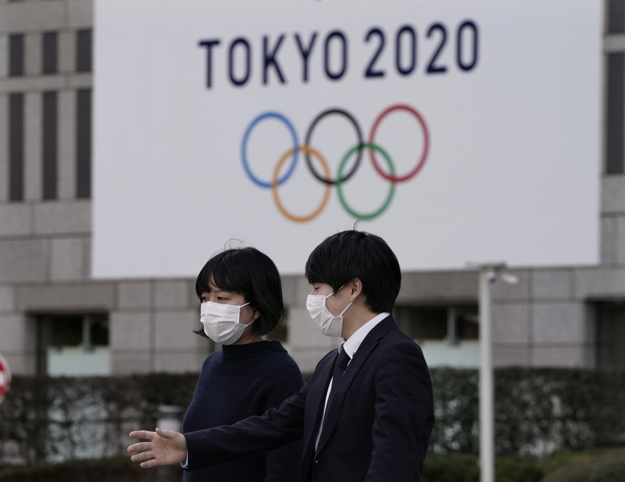 국제올림픽위원회(IOC)는 22일(현지시간) 신종 코로나바이러스 감염증(코로나19) 확산으로 인해 7월 개막 예정이던 도쿄 올림픽의 연기 가능성을 검토하기로 했다. 사진은 도쿄 시민들이 마스크를 낀 채 대형 오륜기 걸개가 설치된 시청을 지나는 모습. [EPA]