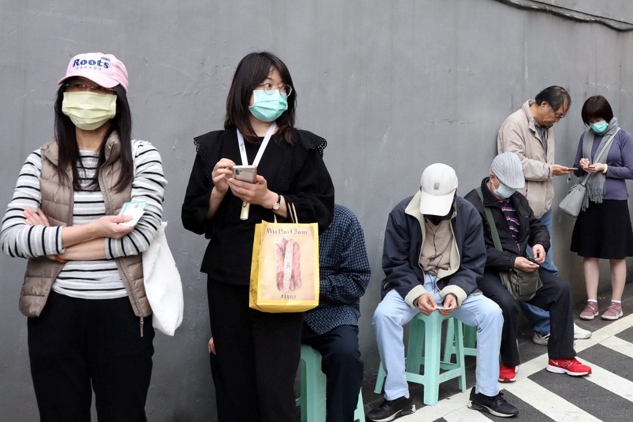 대만의 코로나19 확진자가 200명을 넘어서면서 대만 일부 지방정부에서 자가격리 이탈 방지를 위해 ‘전자팔찌’ 도입을 추진하고 있다. 사진은 타이페이 시민들이 한 약국 앞에서 마스크를 사기 위해 긴 줄을 서서 기다리고 있는 모습. [로이터]