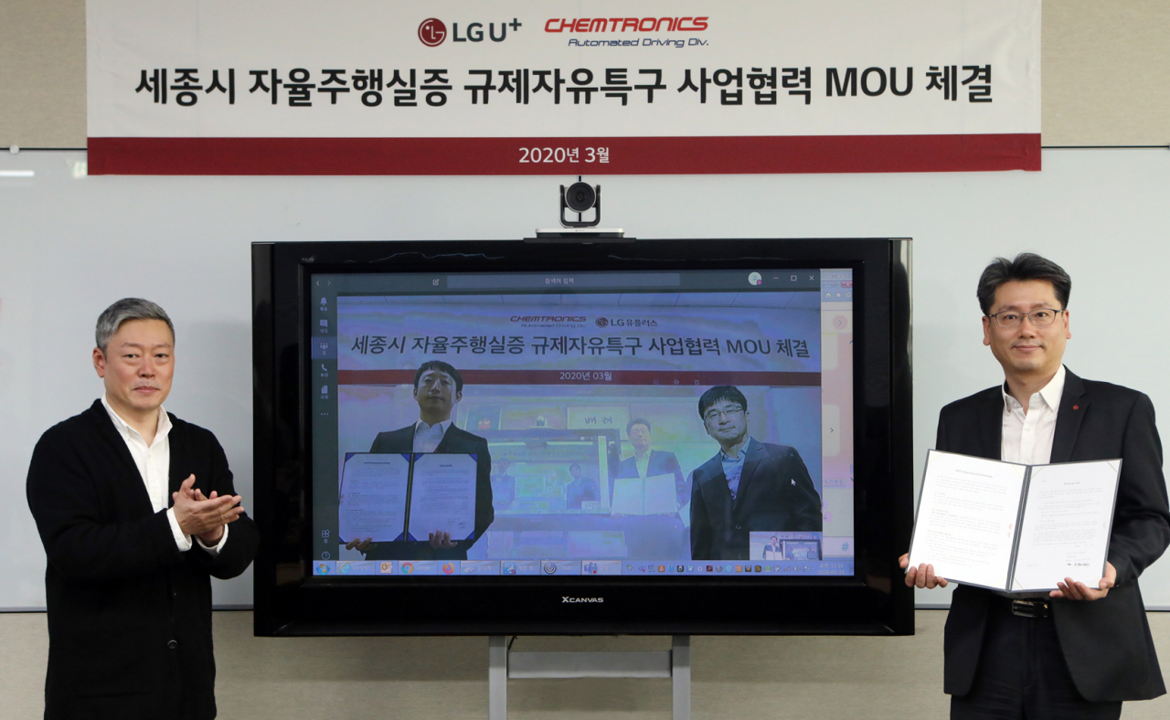 강종오 LG유플러스 모빌리티사업담당 상무(사진 우측)와 김응수 켐트로닉스 자율주행사업부문장 전무(TV속 좌측)가 지난 25일 원격회의를 통해 세종시 자율주행 실증 사업에 대한 업무협약을 맺은 후 기념 사진을 찍고 있다. [LG유플러스 제공]