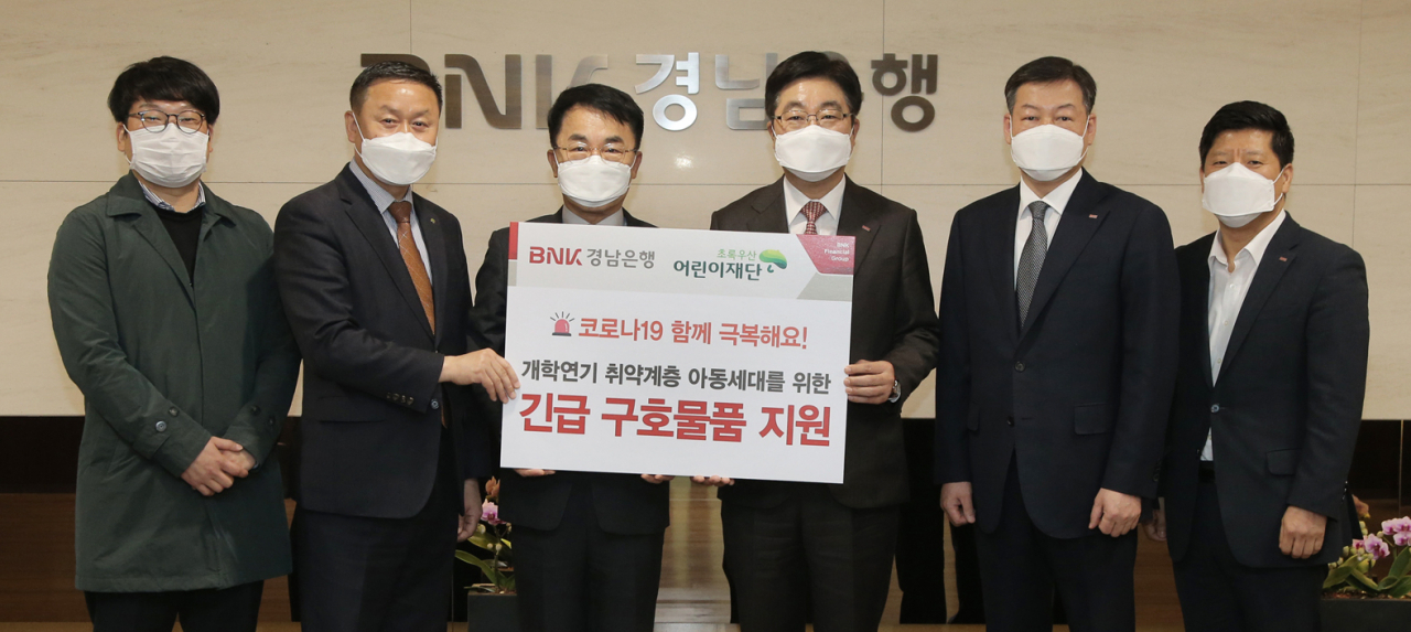 BNK경남은행 황윤철 은행장(오른쪽 세번째)이 초록우산 어린이재단 경남지역본부 정영식 후원회장(오른쪽 네번째)과 박원규 본부장(오른쪽 다섯번째)에게 ‘개학연기 취약계층 아동 구호물품 기탁 증서’를 전달하고 있다.