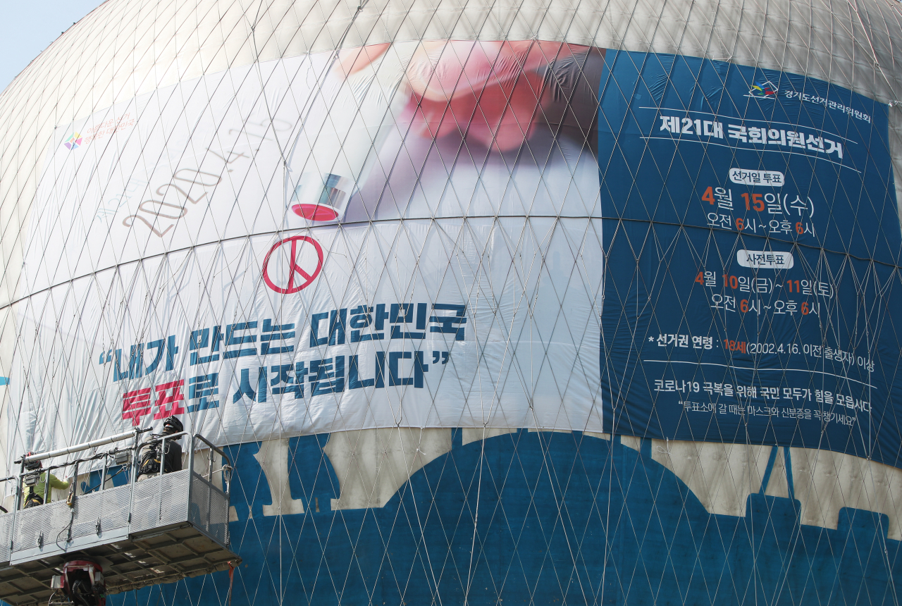 지난 25일 경기도 수원시 팔달구 헬륨 기구 플라잉수원에서 관계자들이 제21대 국회의원선거를 알리는 현수막을 설치하고 있다. [연합]