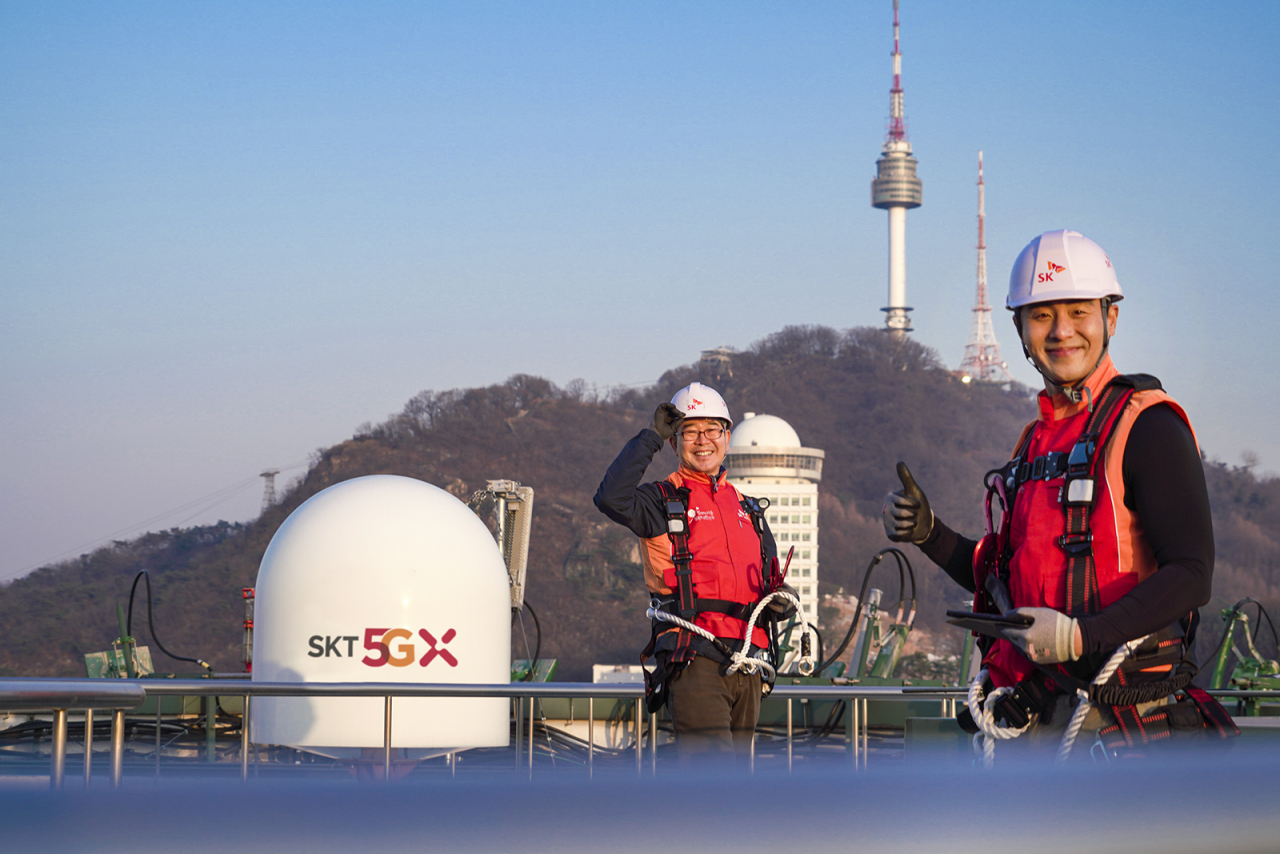 SK텔레콤 홍보모델들이 서울에 위치한 한 빌딩 위에서 5G 기지국을 점검하며 5G 상용화 1주년을 기념해 포즈를 취하고 있다. [SK텔레콤 제공]