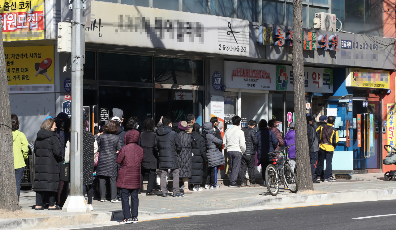 일요일인 지난 22일 오전 서울 구로구의 한 약국에서 시민들이 출생 연도와 상관없이 판매되는 공적 마스크를 사기 위해 길게 줄을 서 있다. [연합]