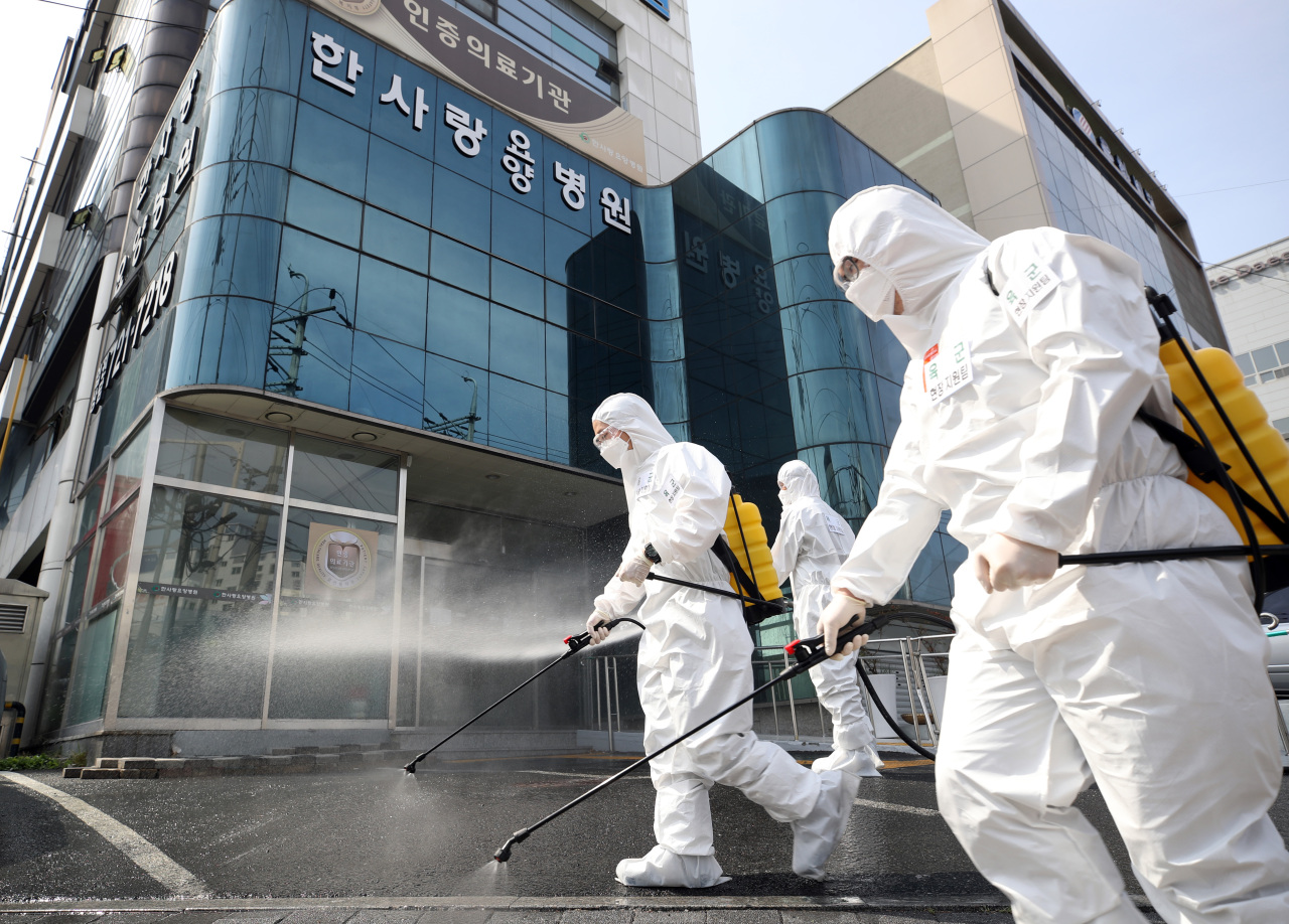 South Korean soldiers wearing protective gear sanitize a street in front of a hospital in Daegu on Monday. (Yonhap)