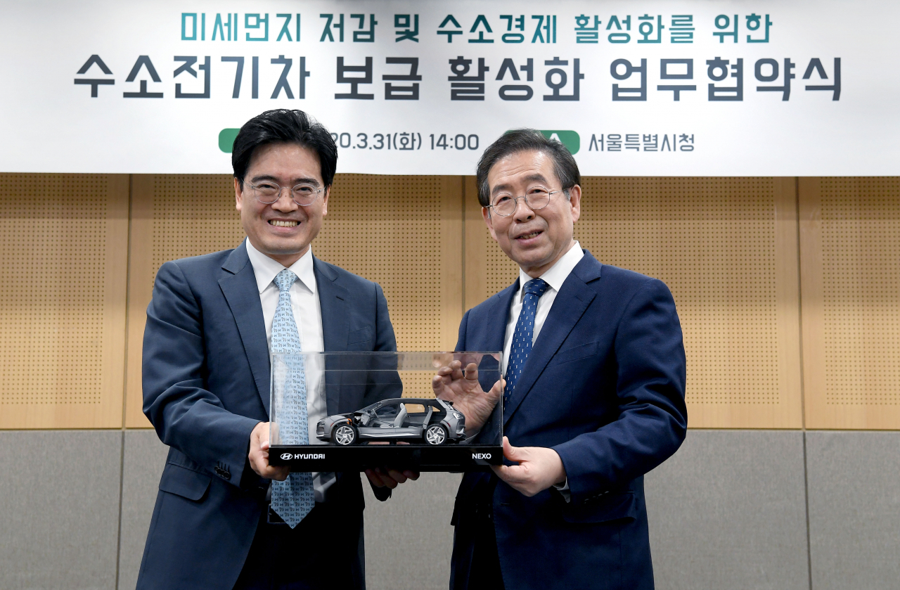 현대차 공영운 사장(왼쪽)과 서울시 박원순 시장(오른쪽)이 수소전기차 넥쏘 절개차 모형을 들고 기념촬영을 하고 있다. [현대차 제공]
