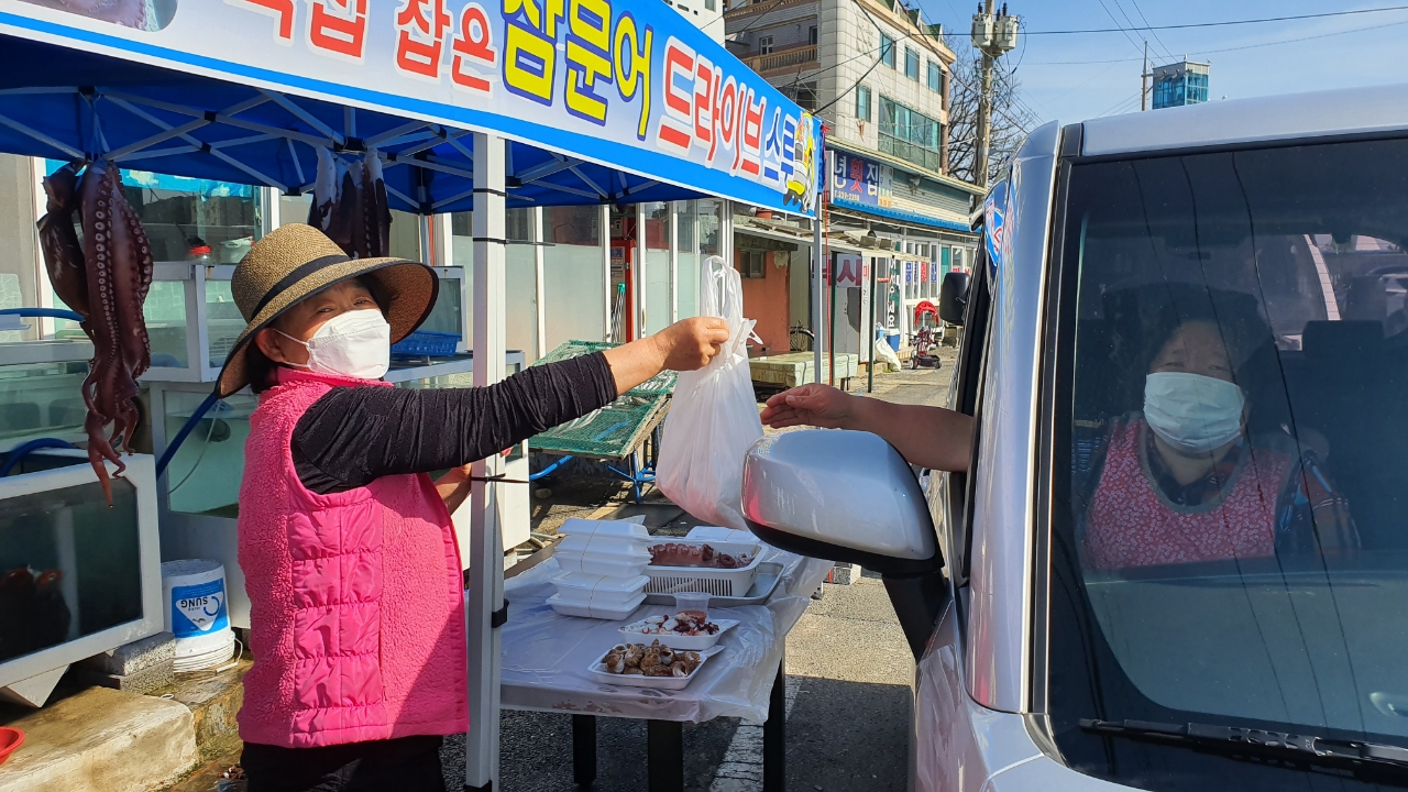 한 어민이 손님이 주문한 회를 다듬어 차 속으로 전달하고 있다.